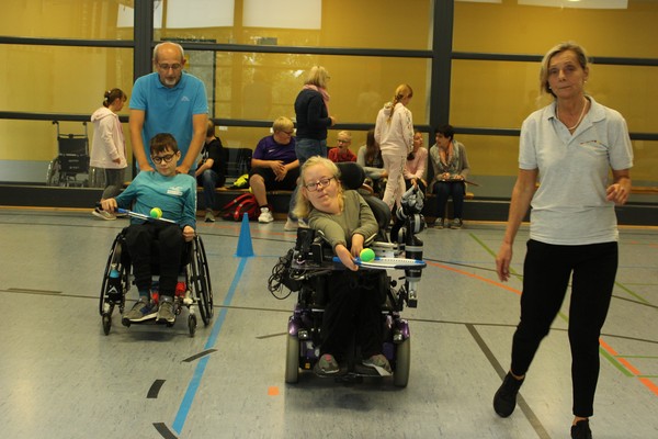 Ein Foto zeigt Brückenschüler:innen, die in der Sporthalle einen Parcours fahren.